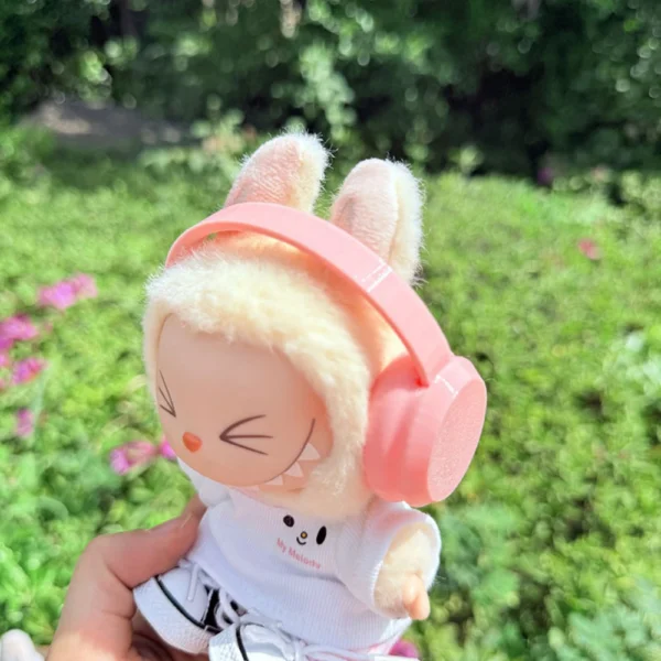 Cute Labubu Doll Wearing a pink Headphone in a Natural Green Setting - Adorable Earphone Accessory | Labubu Doll Clothing & Accessories