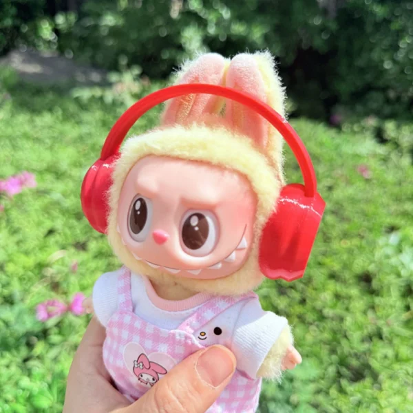 Cute Labubu Doll Wearing a Red Headphone in a Natural Green Setting - Adorable Earphone Accessory | Labubu Doll Clothing & Accessories