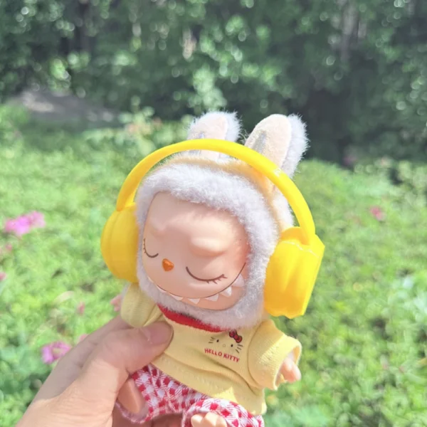 Cute Labubu Doll Wearing a Yellow Headphone in a Natural Green Setting - Adorable Earphone Accessory | Labubu Doll Clothing & Accessories